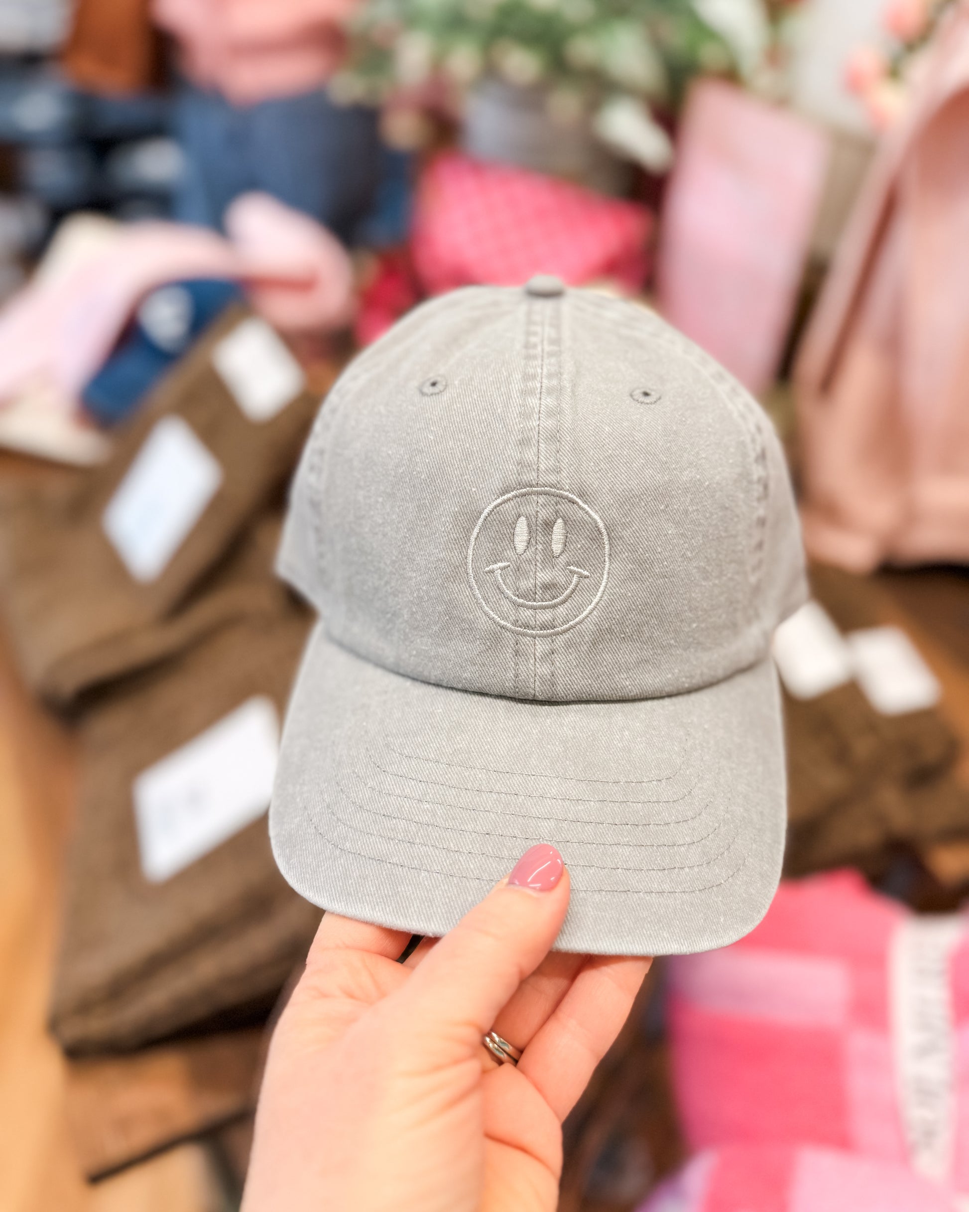 Gray cap with a logo held by a hand against a blurred indoor background