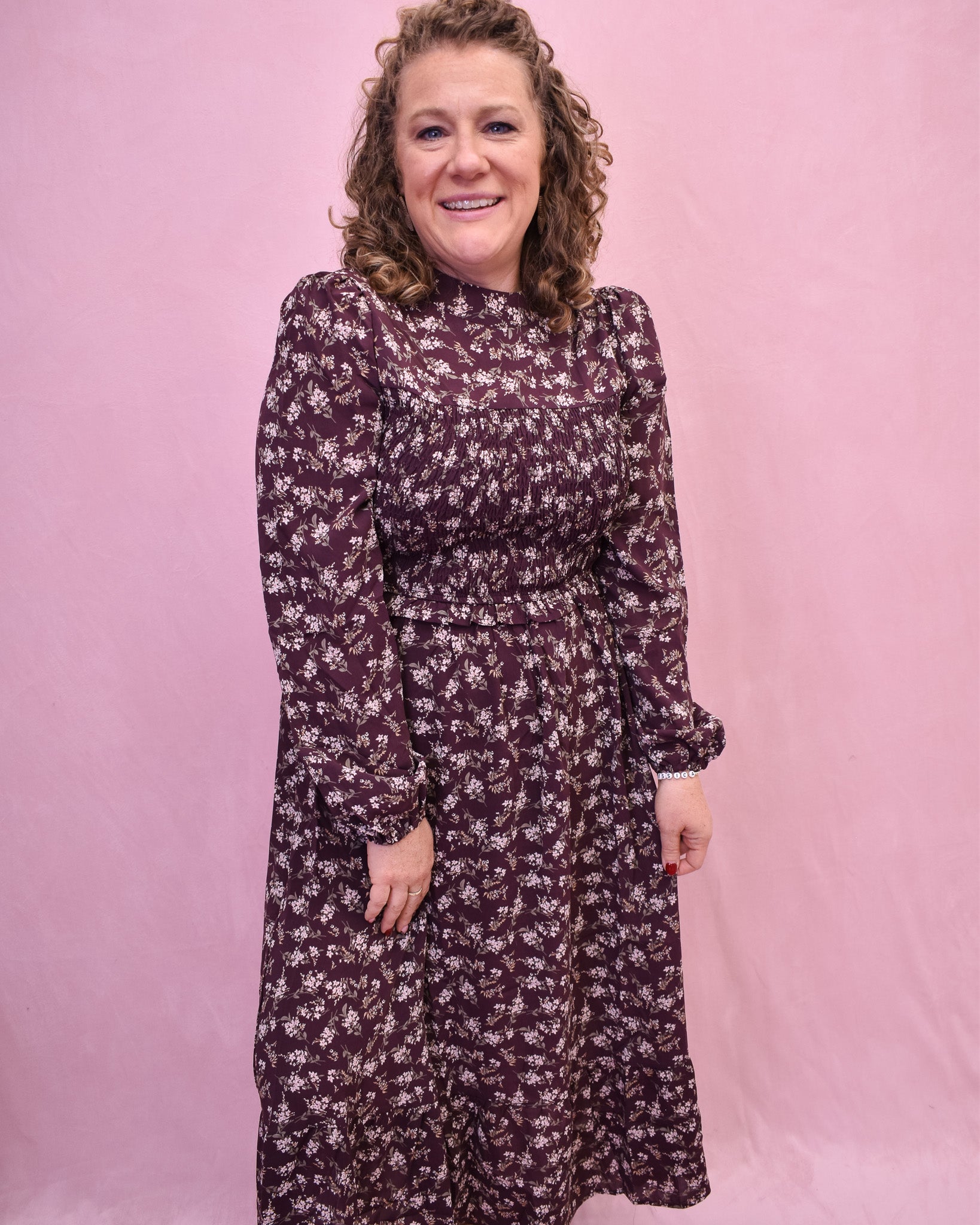 Woman wearing a floral dress against a pink background