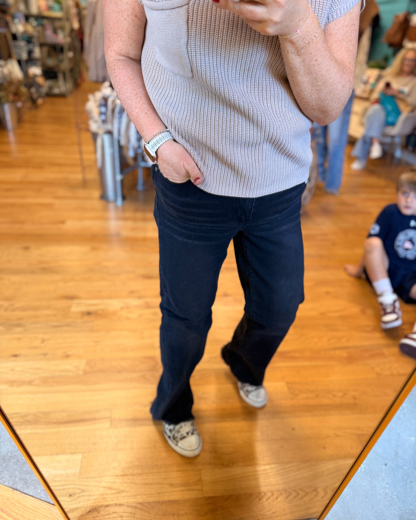Person wearing a light blue sweater and dark blue jeans standing in a store.