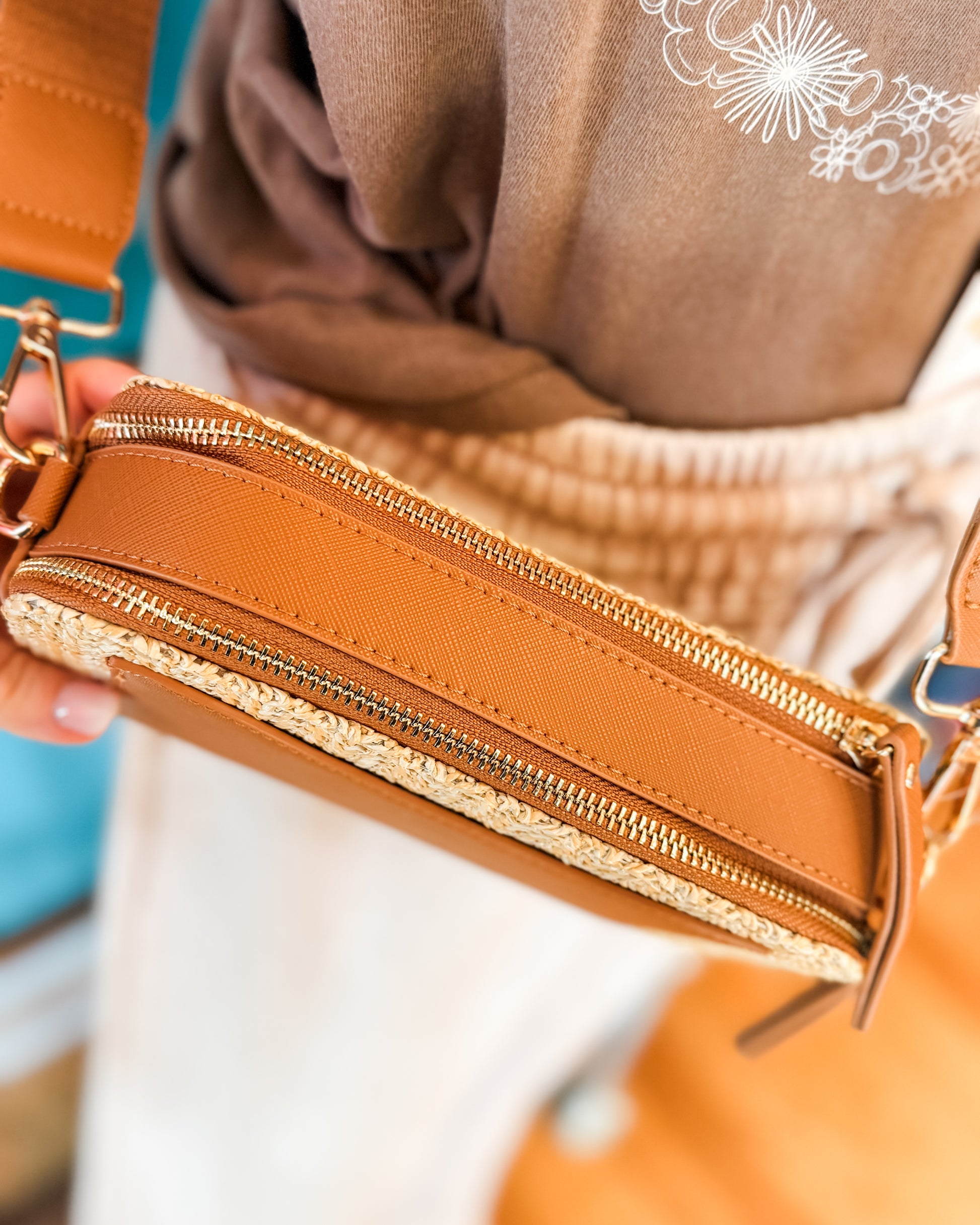 Close-up of a brown leather crossbody bag with gold zipper