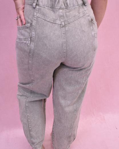 Gray jeans worn by a person on a pink background