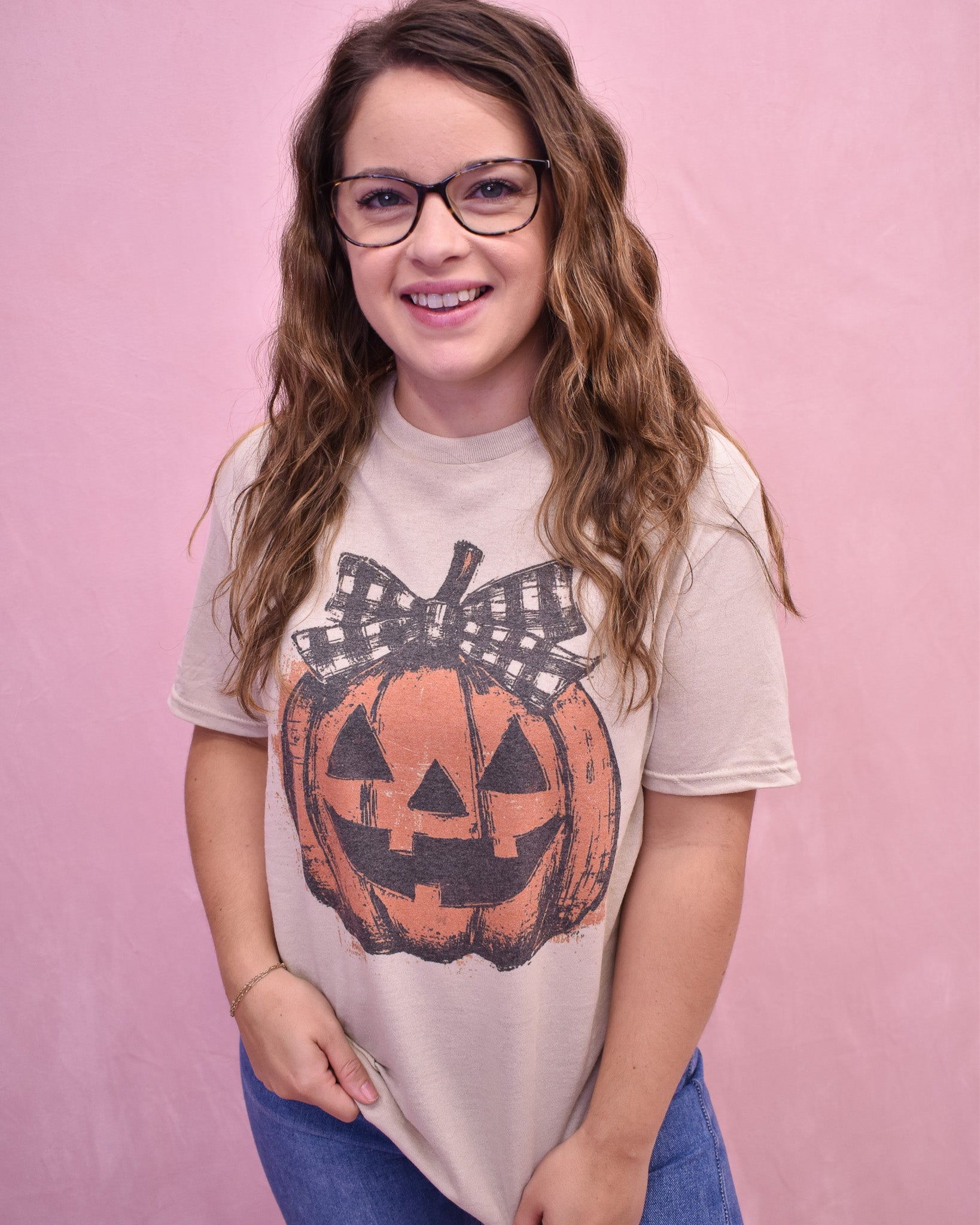 Person wearing a t-shirt with a pumpkin design on a pink background