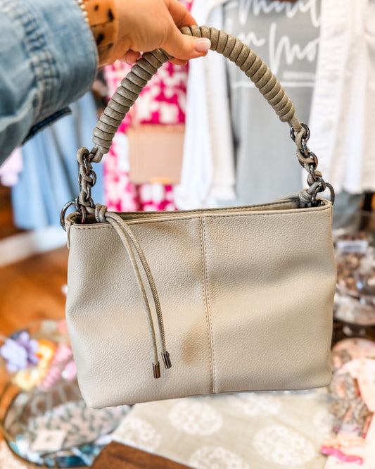 Medium handbag in a light sage green with a woven chain like leather handle.