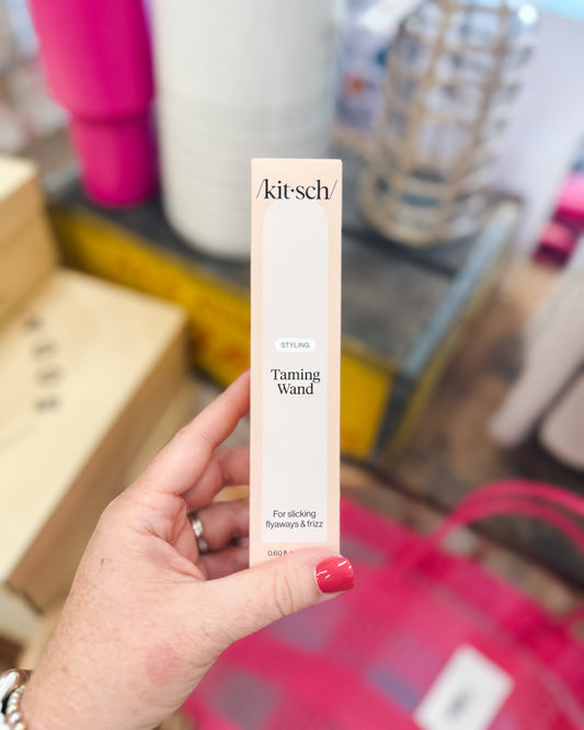 Kitsch Taming Wand product held by a hand with a blurred background