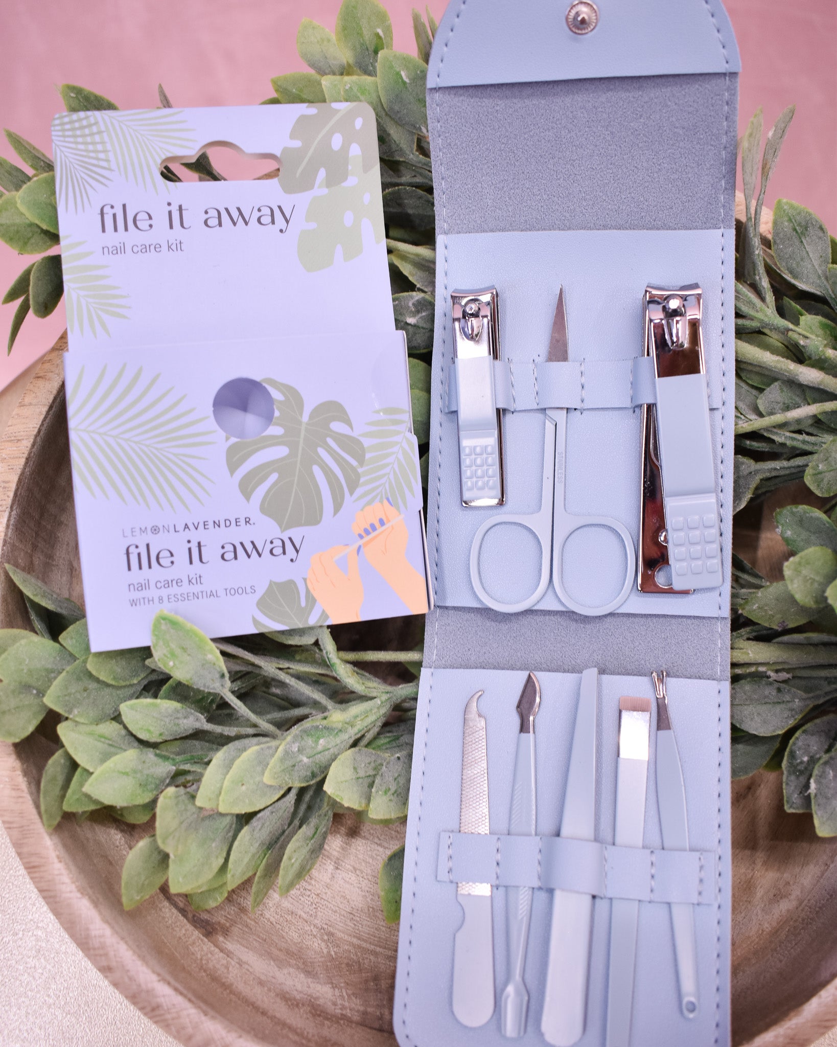 Manicure set with tools and packaging on a leafy background