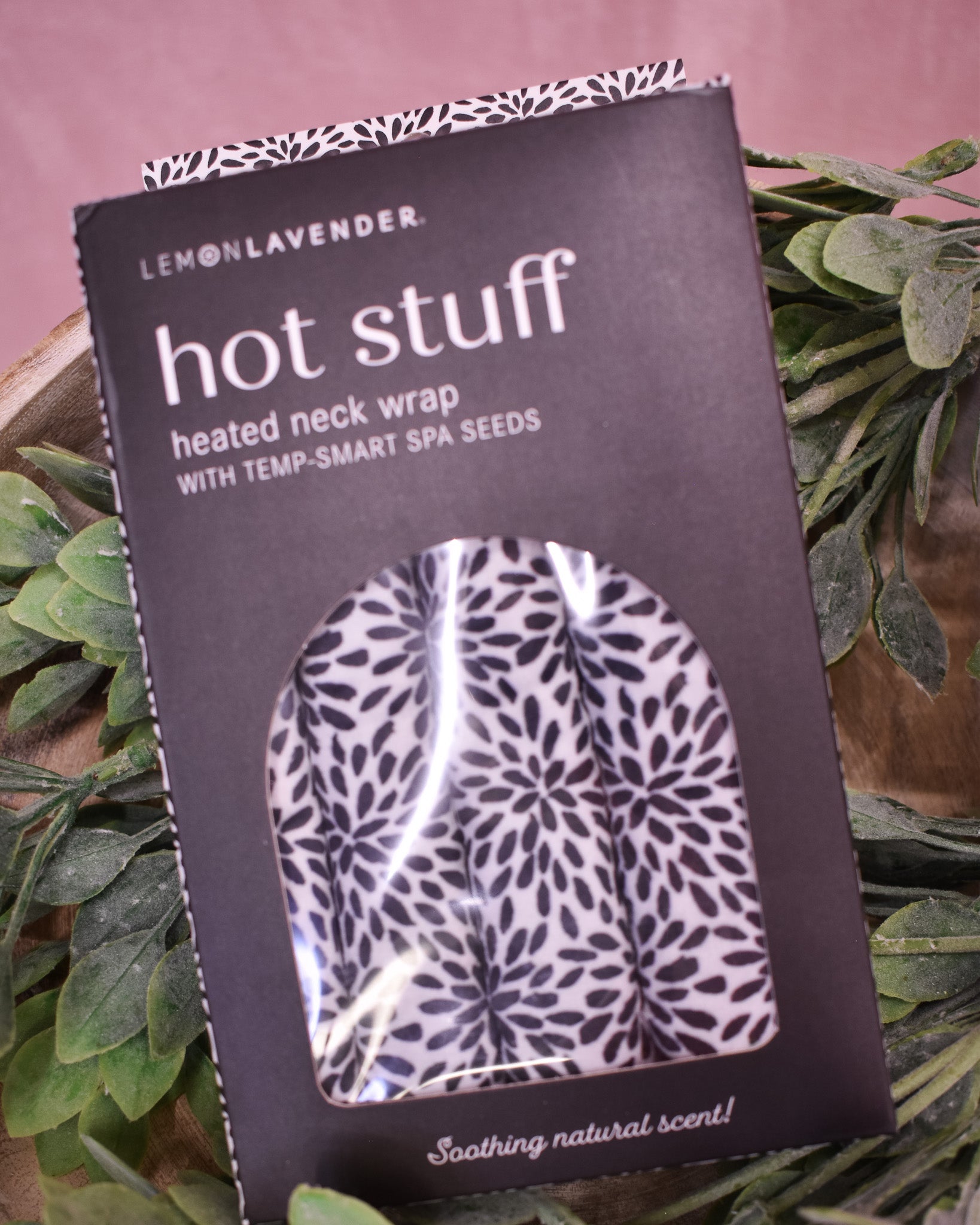 Packaged heated neck wrap with floral pattern on a pink background