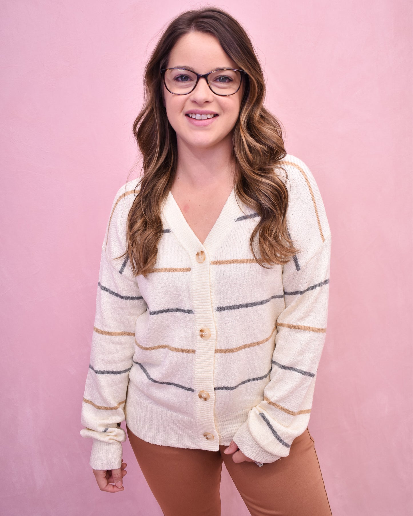 Woman wearing a striped cardigan against a pink background