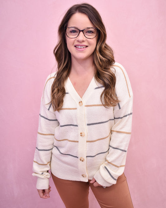 Woman wearing a striped cardigan against a pink background
