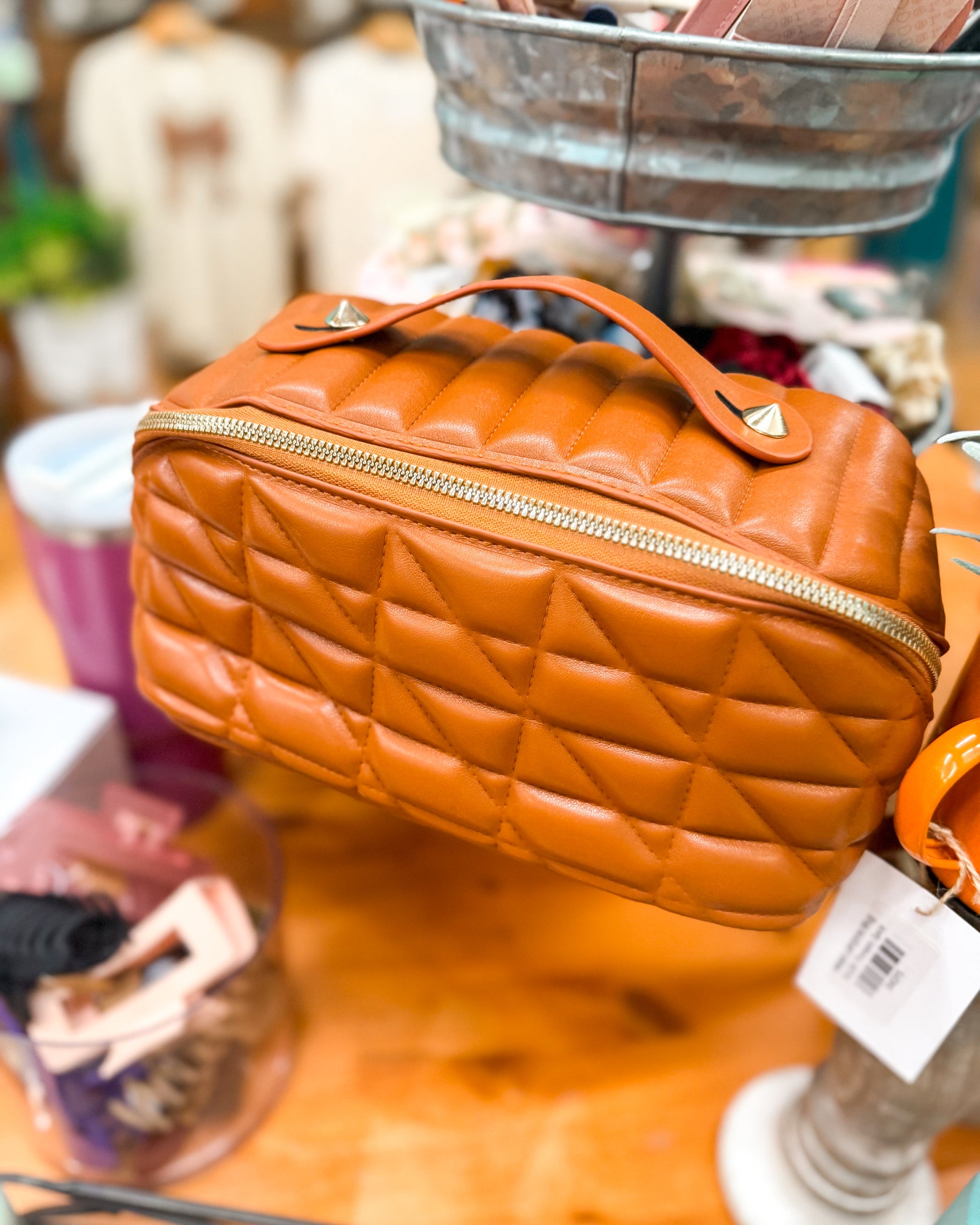 Quilted orange handbag on a wooden surface with a blurred background