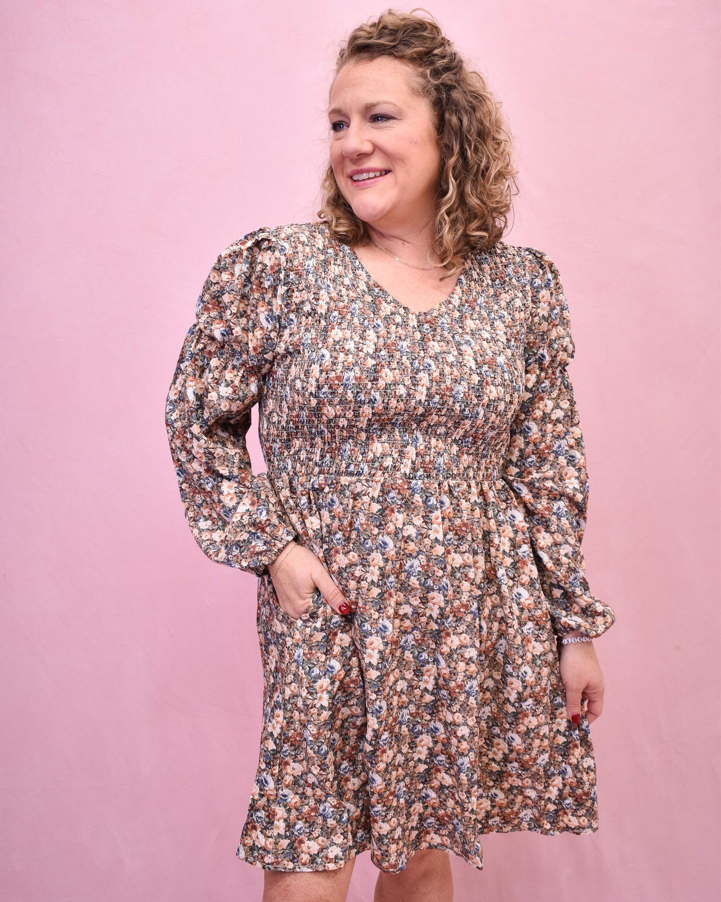 Woman wearing a floral dress against a pink background
