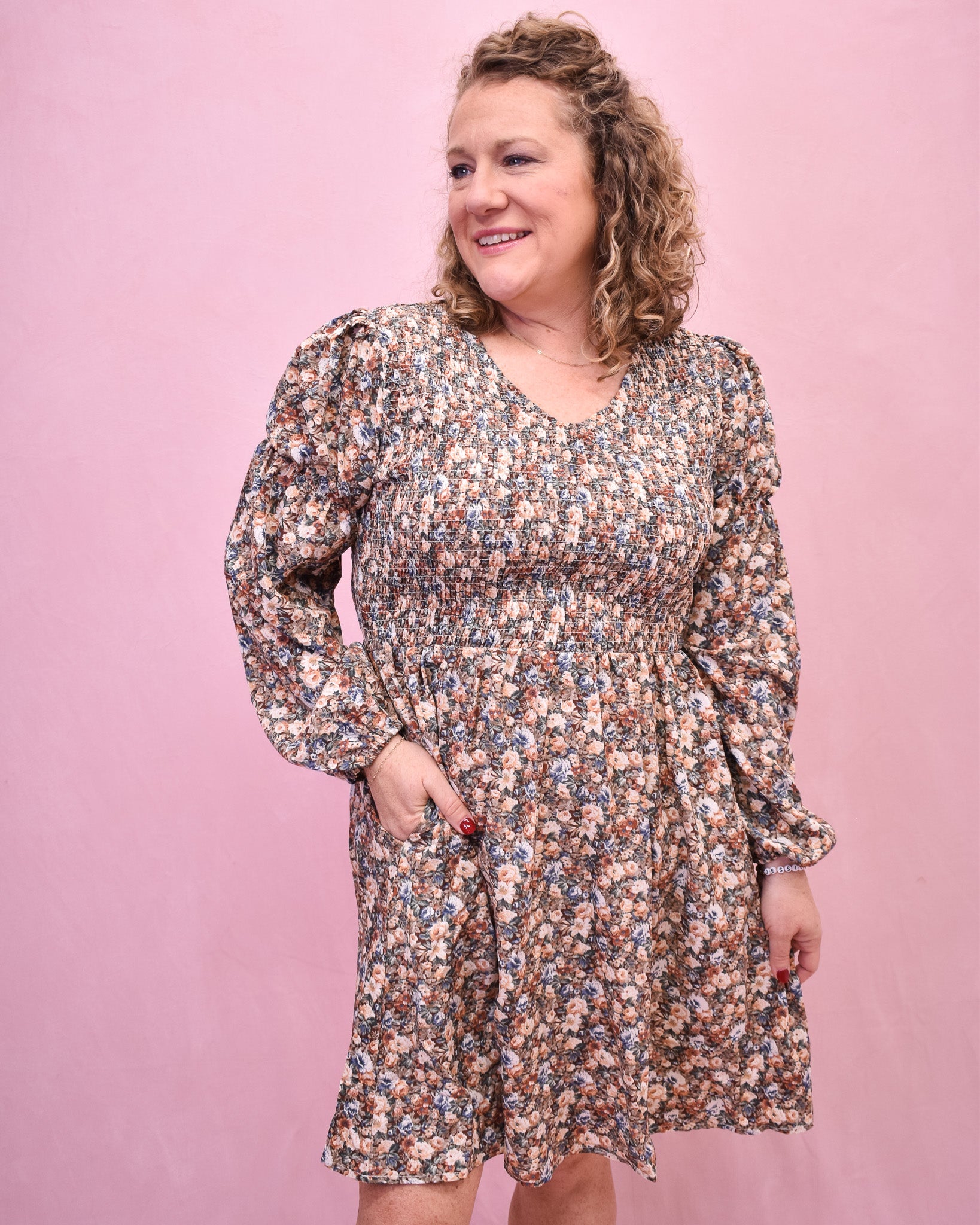 Woman wearing a floral dress against a pink background