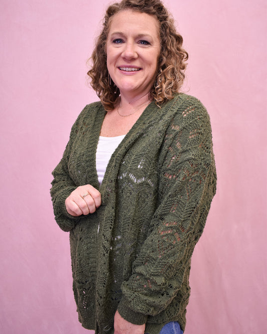 Woman wearing a green cardigan against a pink background