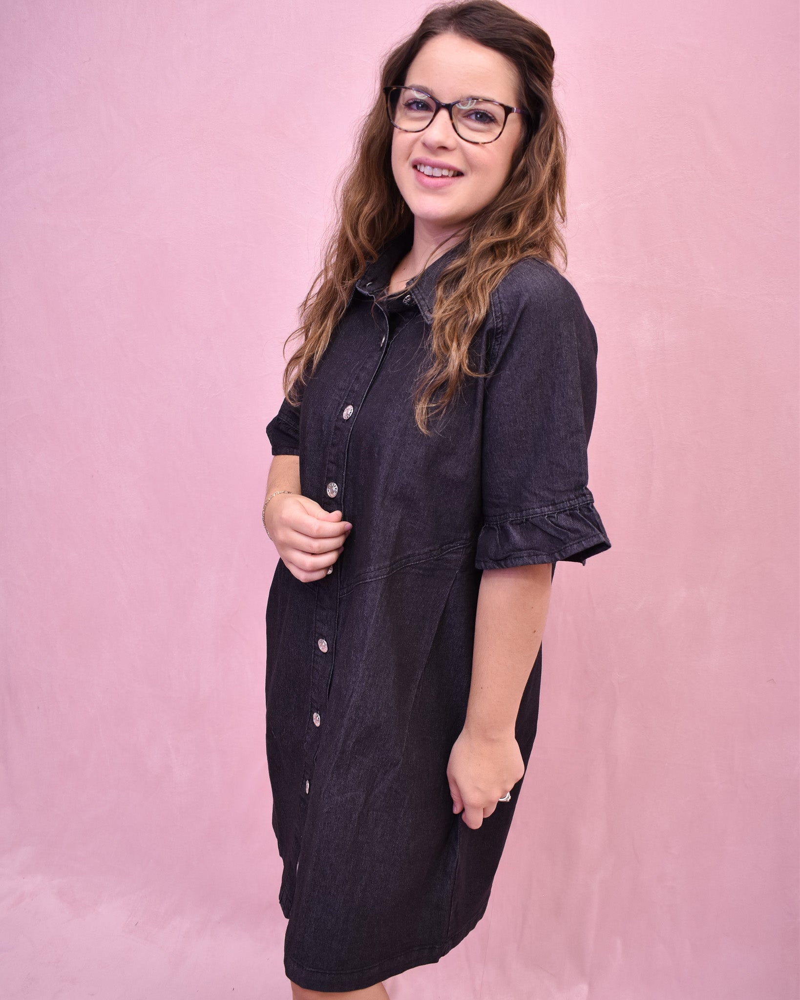 Woman wearing a black dress against a pink background