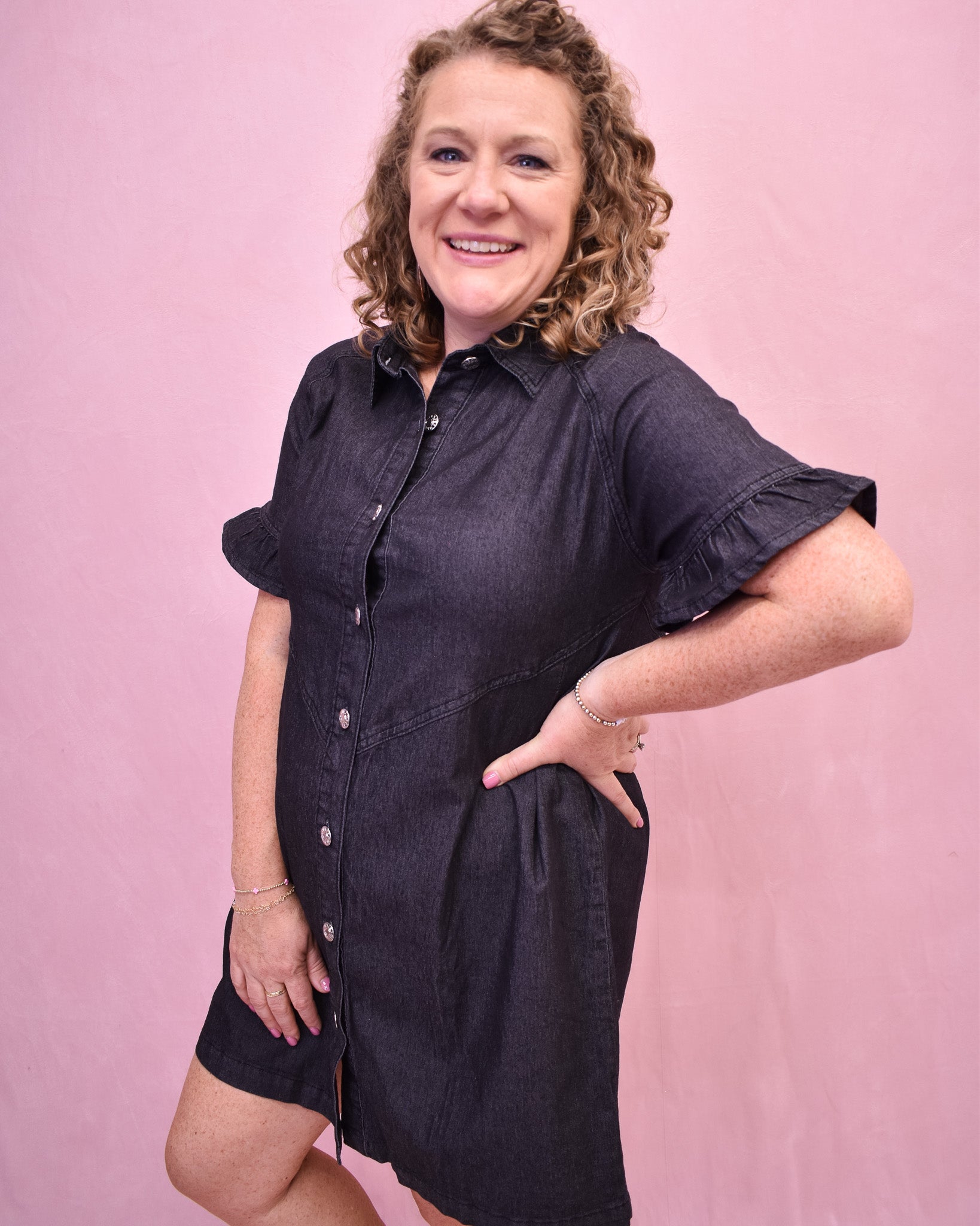Woman wearing a black dress against a pink background