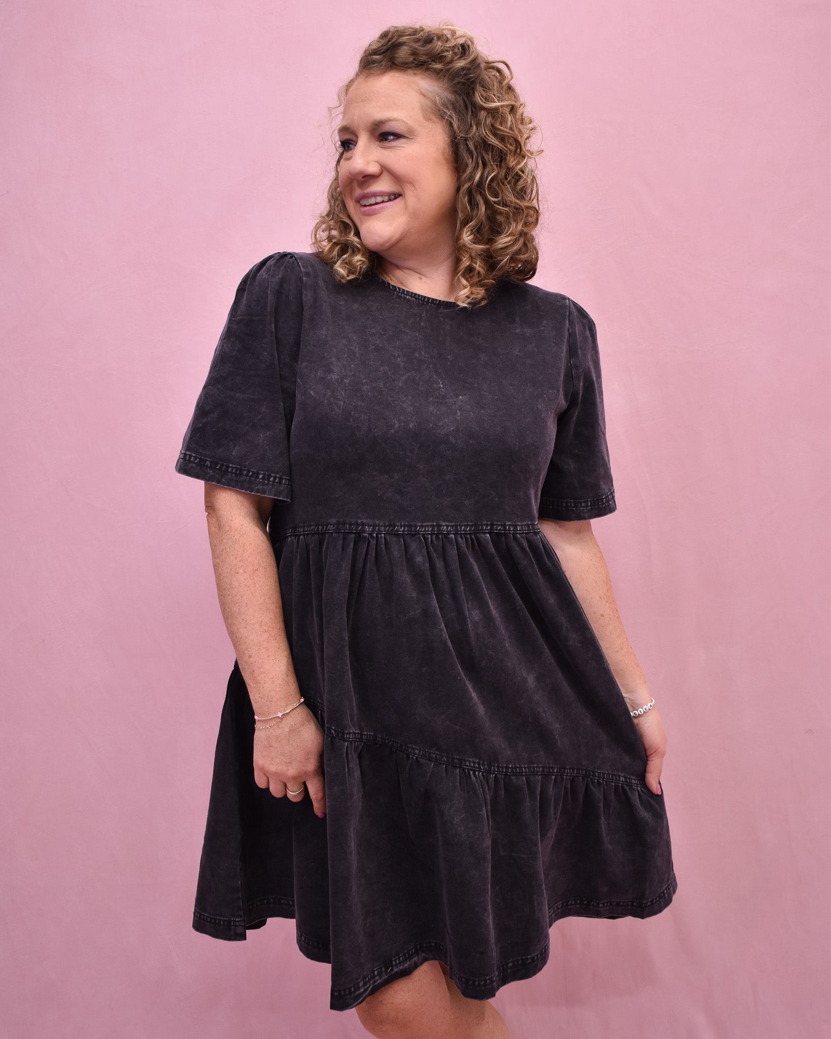 Woman wearing a black dress against a pink background