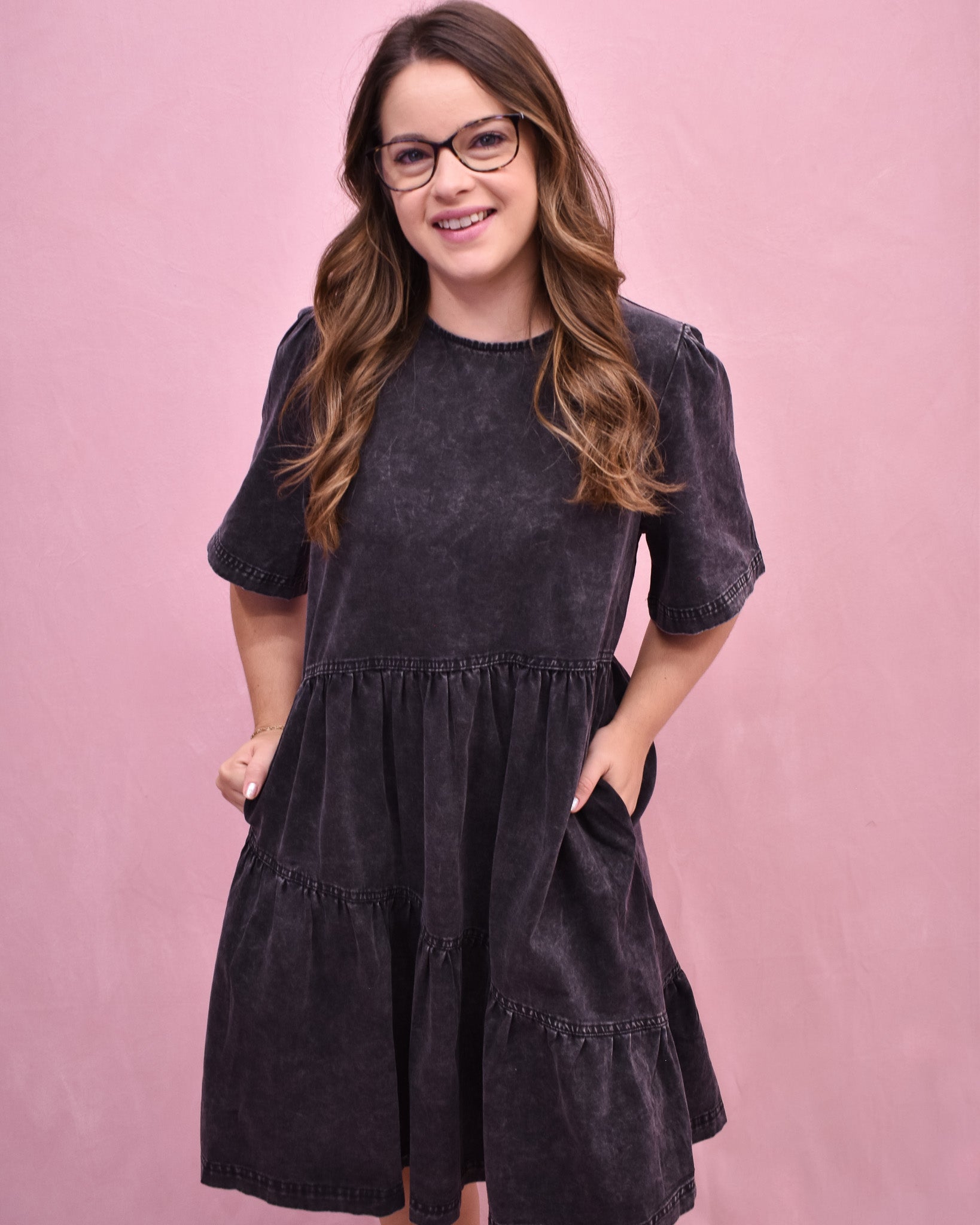 Woman wearing a dark gray dress against a pink background