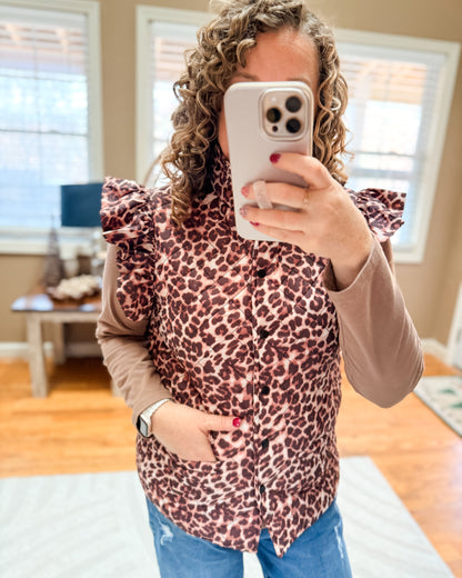 Person wearing a leopard print top in a room with wooden flooring and windows.