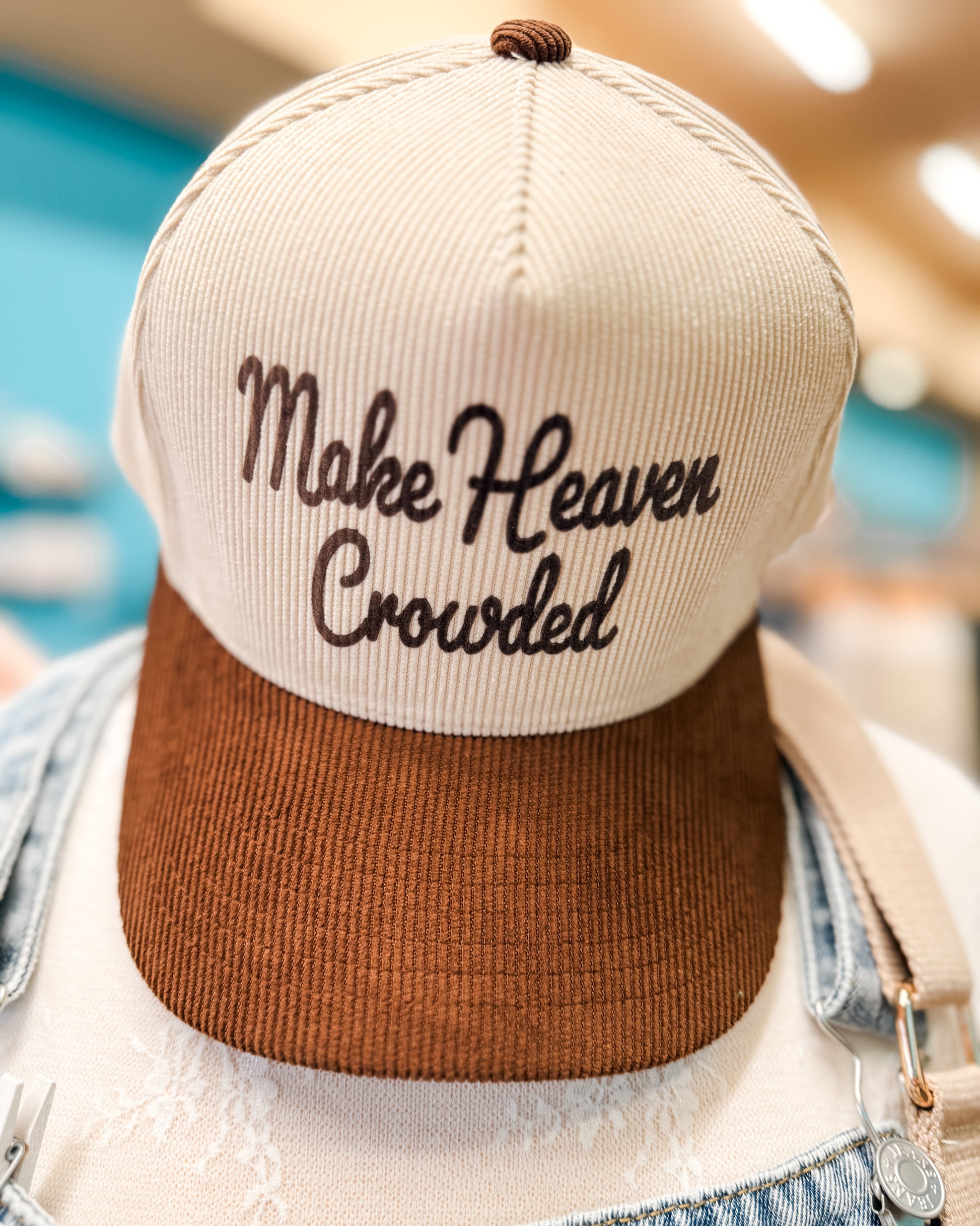Beige and brown cap with 'Make Heaven Crowded' text on a blurred background