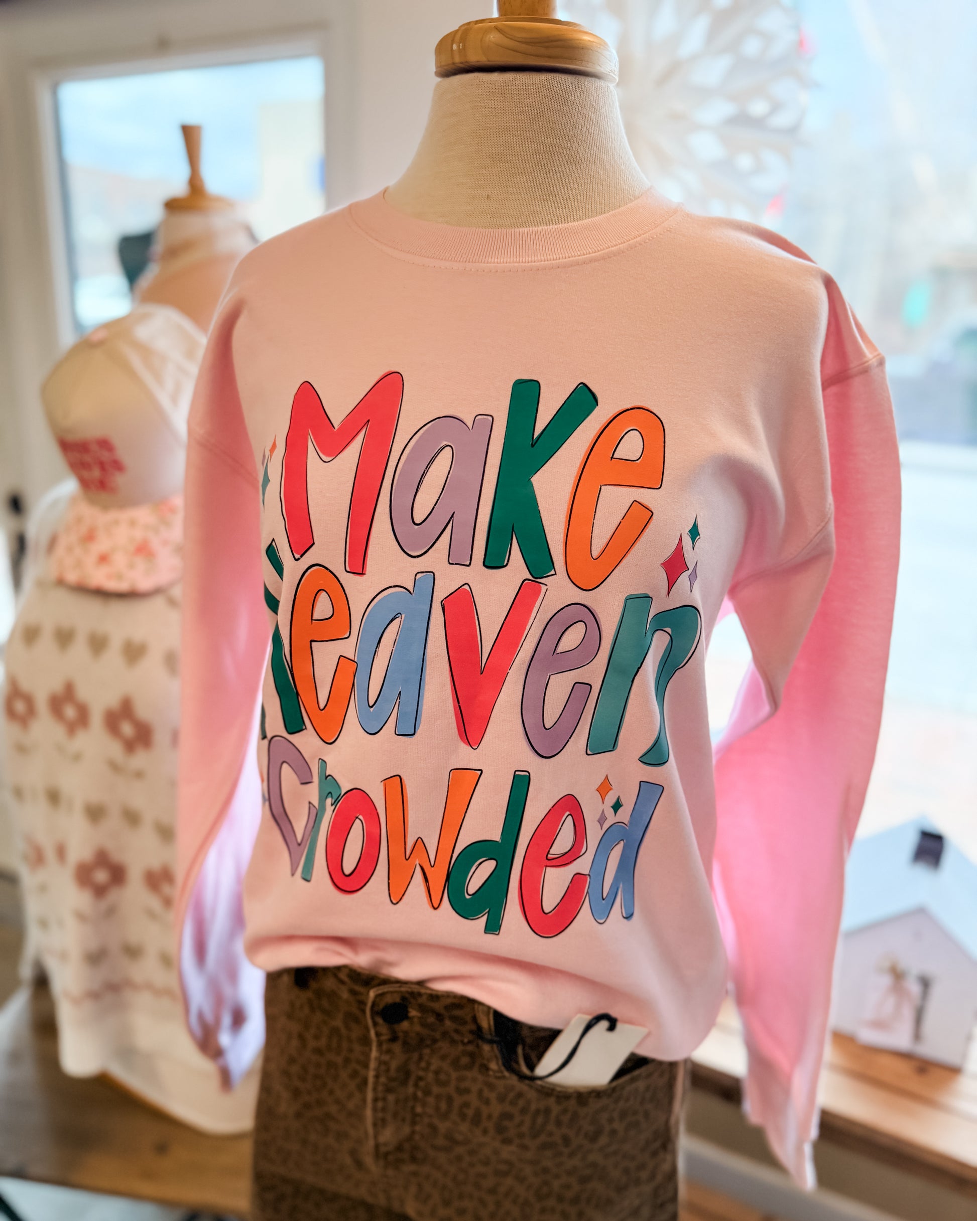 Pink sweatshirt with colorful text on a mannequin in a store setting