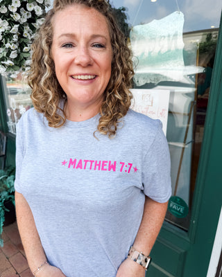 A graphic tee with pink matthew 7:7 bible verse on front