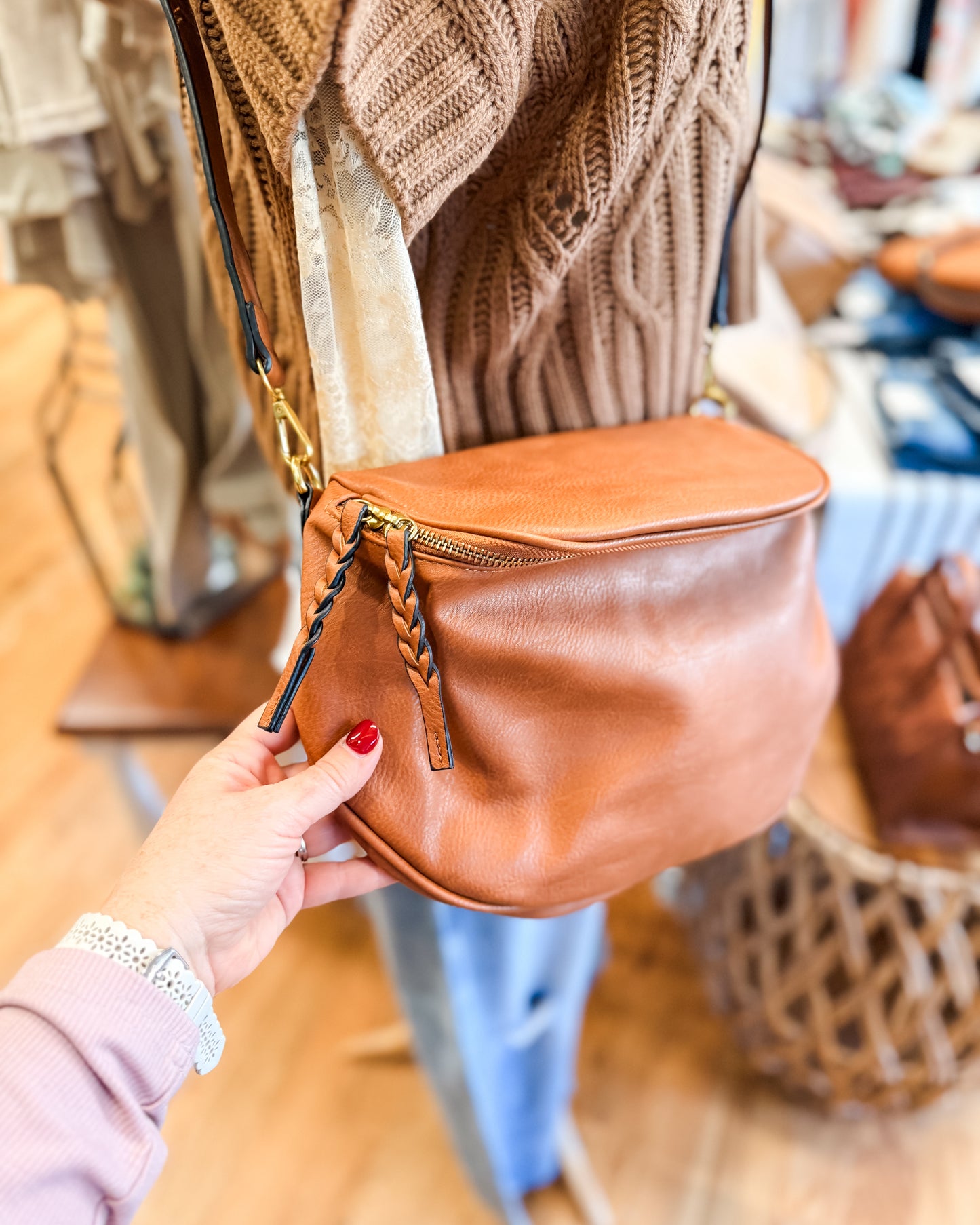 Person holding a brown leather bag in a store setting