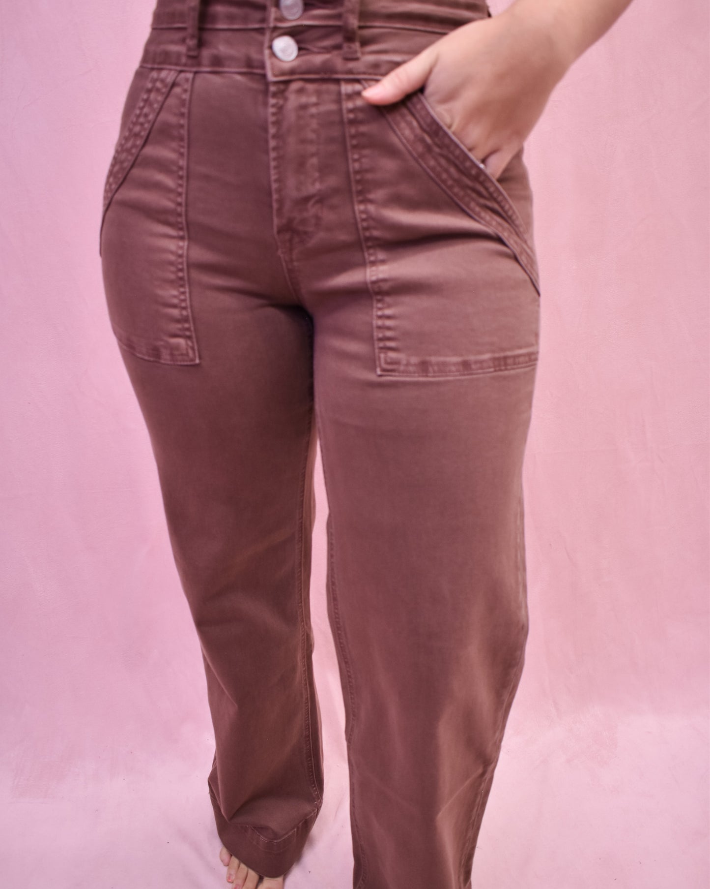 Brown pants worn by a person on a pink background