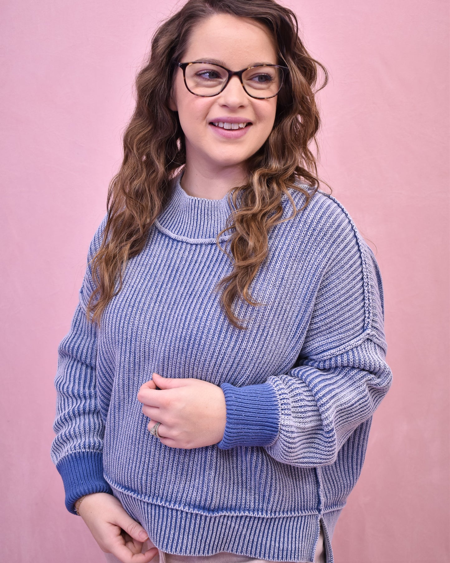 Woman wearing a blue sweater against a pink background