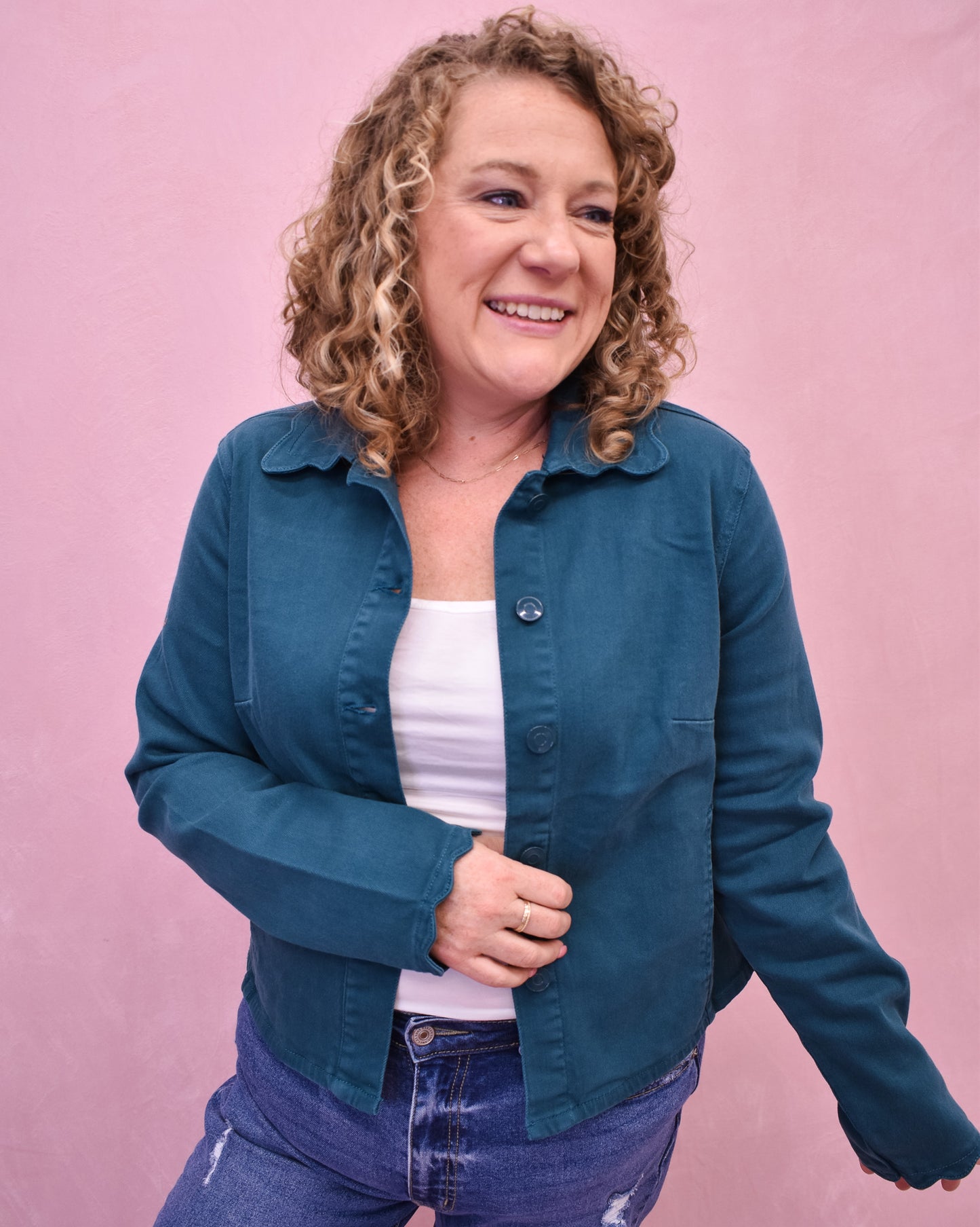 Woman wearing a blue jacket over a white shirt on a pink background