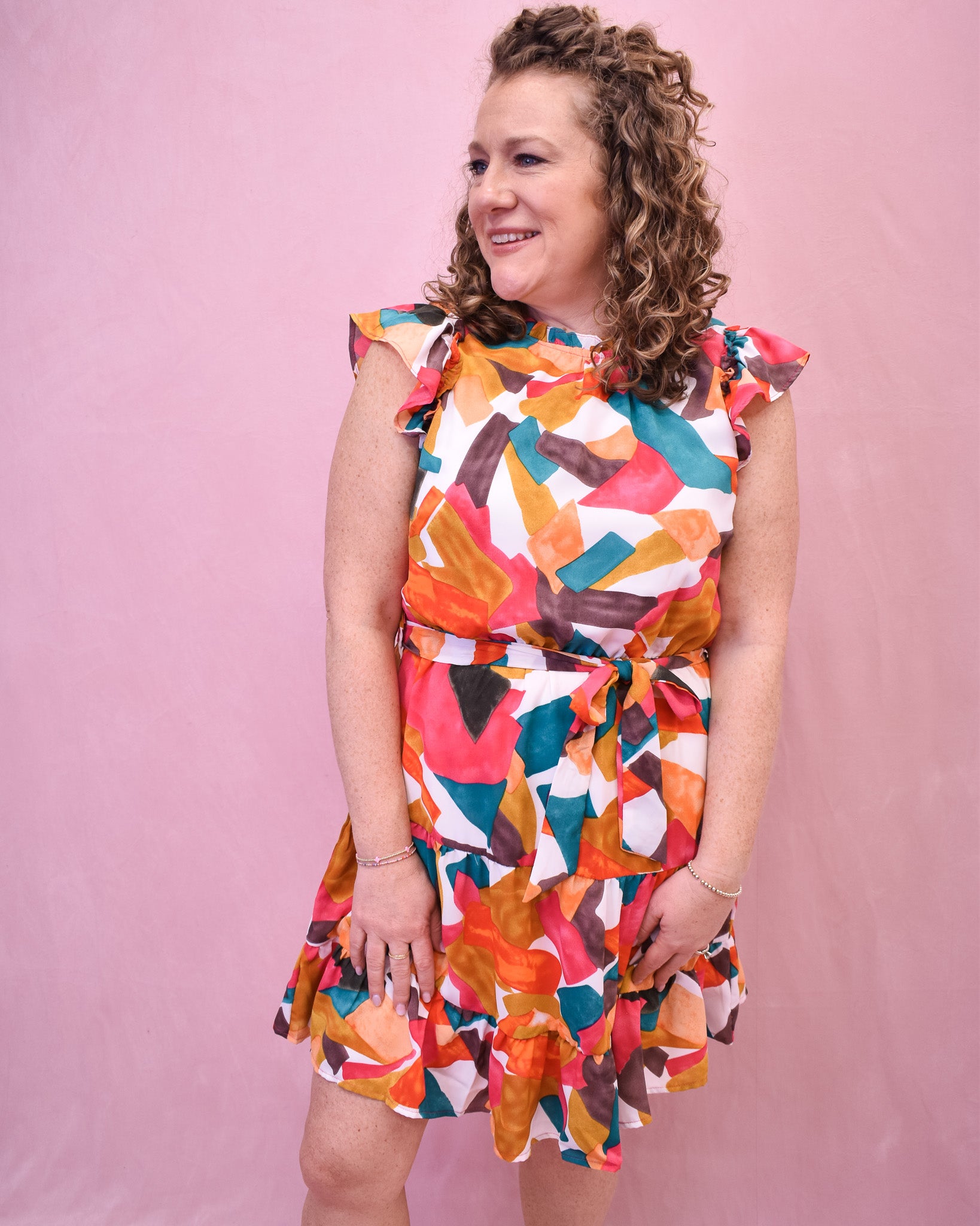  a brush painted multi color design dress with a flutter sleeve, ruffle hem, and tie waist.