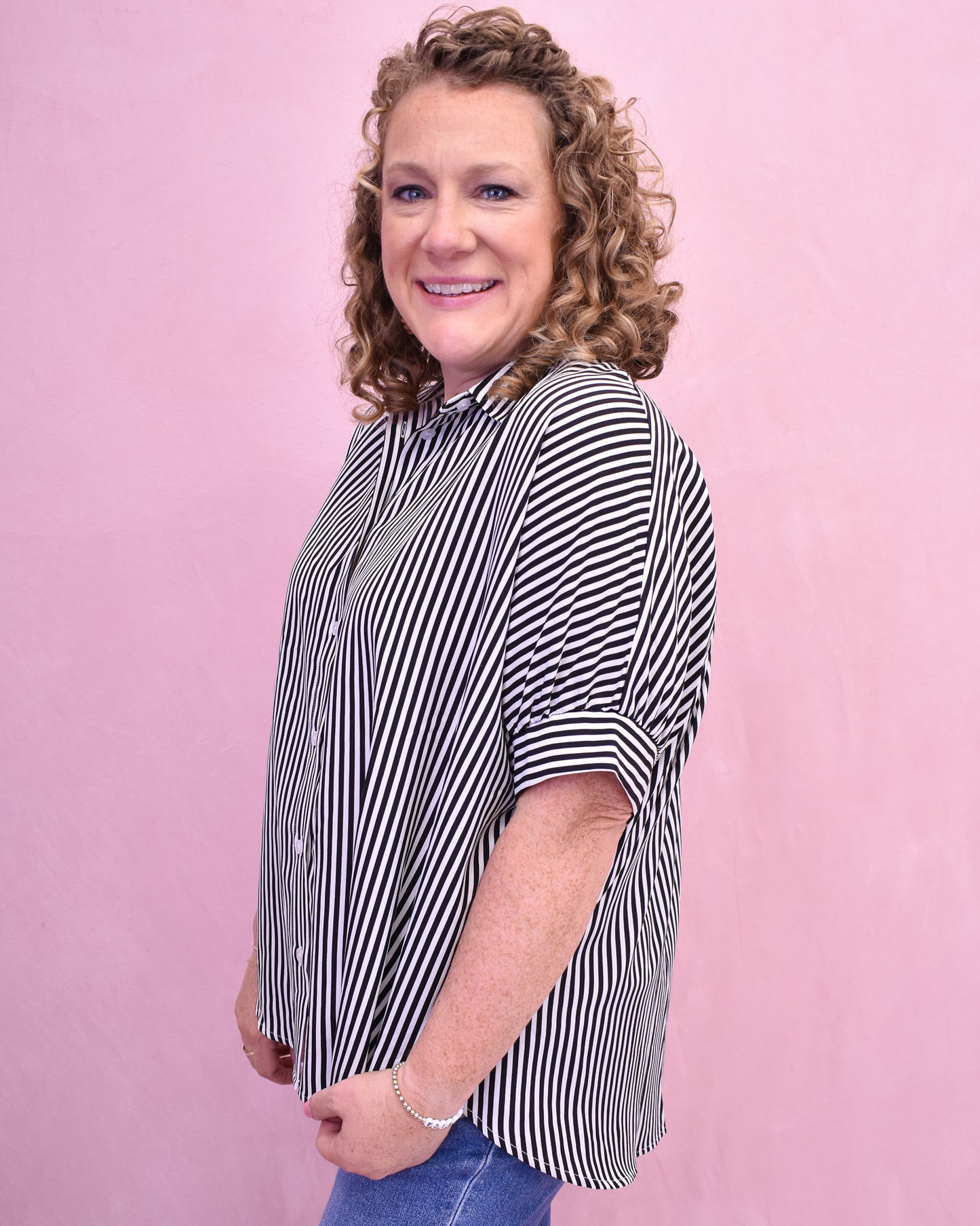 Woman wearing a black and white striped shirt against a pink background