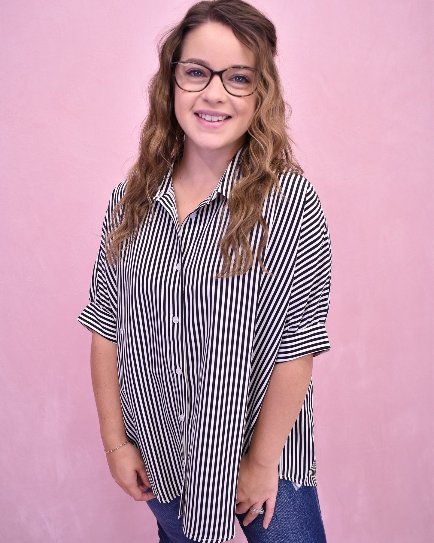 Woman wearing a black and white striped shirt against a pink background