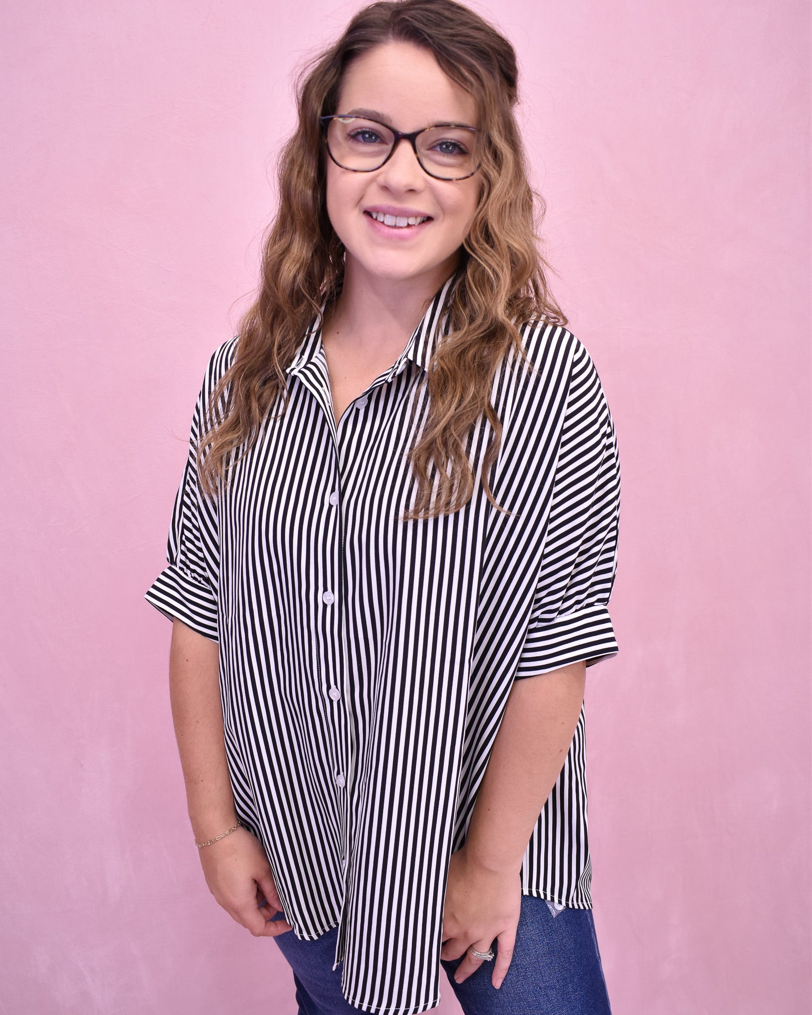 Woman wearing a black and white striped shirt against a pink background