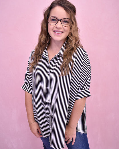 Woman wearing a black and white striped shirt against a pink background