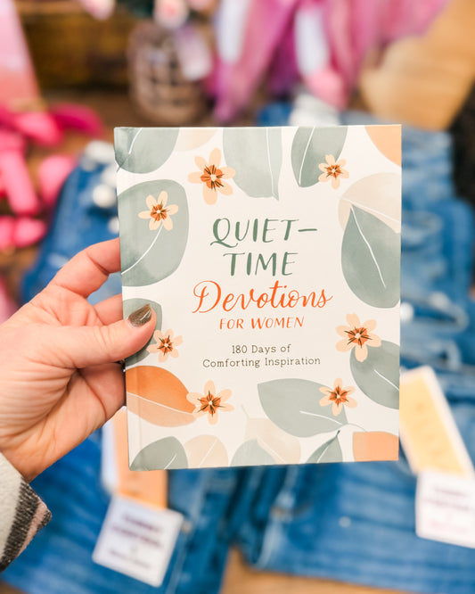 Hand holding a book titled 'Quiet Time Devotions for Women' with floral design.
