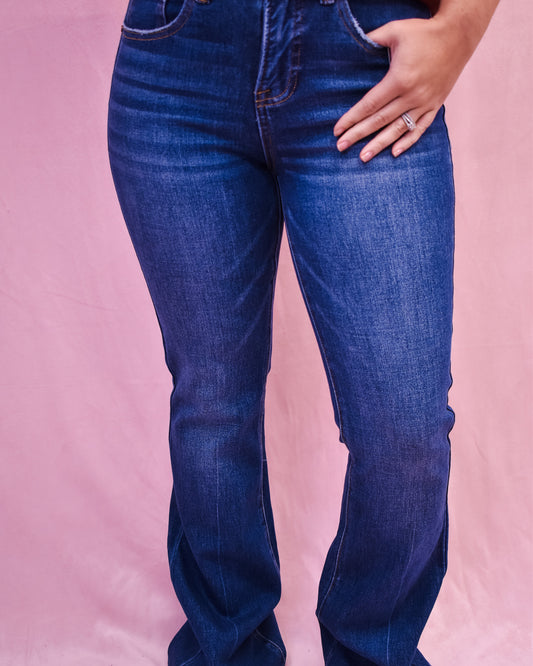 Blue jeans worn by a person on a pink background
