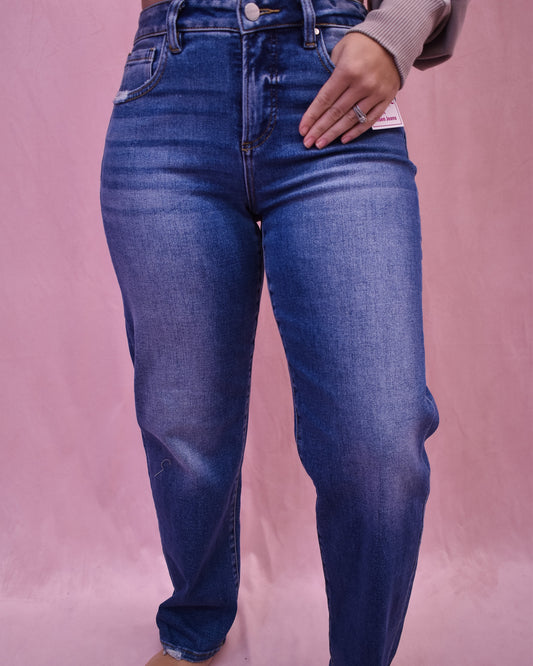 Person wearing blue jeans on a pink background