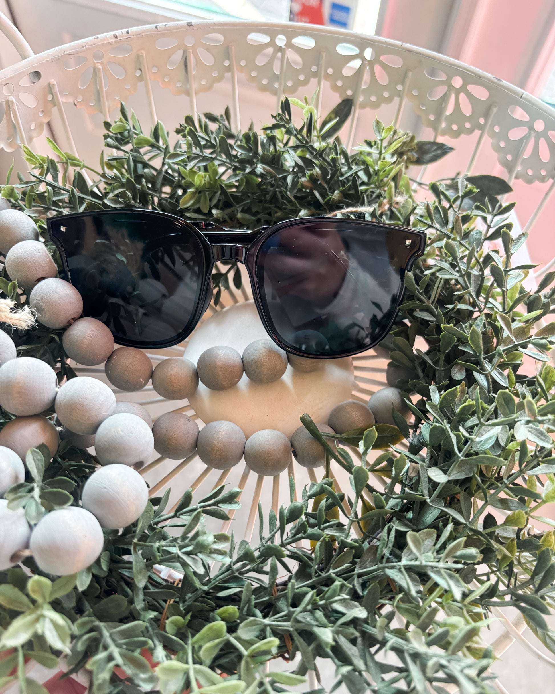 Black sunglasses on a decorative wreath with greenery and beads