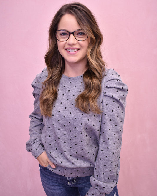 Woman wearing a gray polka dot hoodie against a pink background