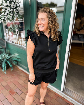 Soft Luxe-Cotton two-piece short set featuring a ruffled half-zip sweatshirt and matching shorts. A comfortable, feminine lounge set perfect for travel, errands, and everyday casual style.