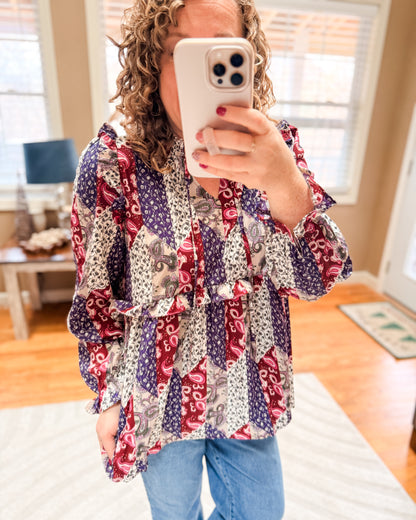 Person wearing a colorful patterned blouse taking a mirror selfie.