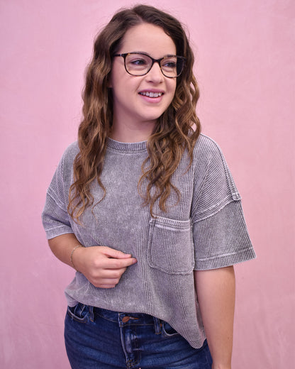 Woman wearing a striped shirt and jeans against a pink background