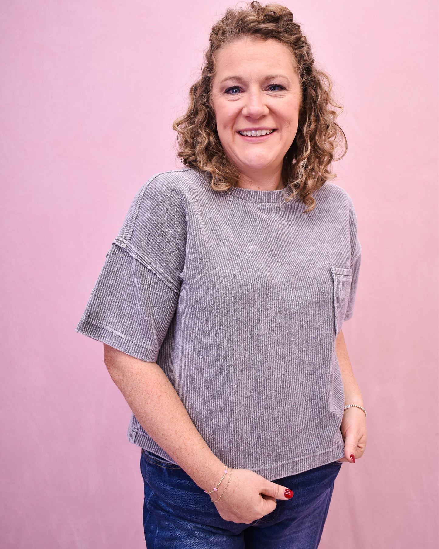 Woman wearing a gray striped shirt against a pink background