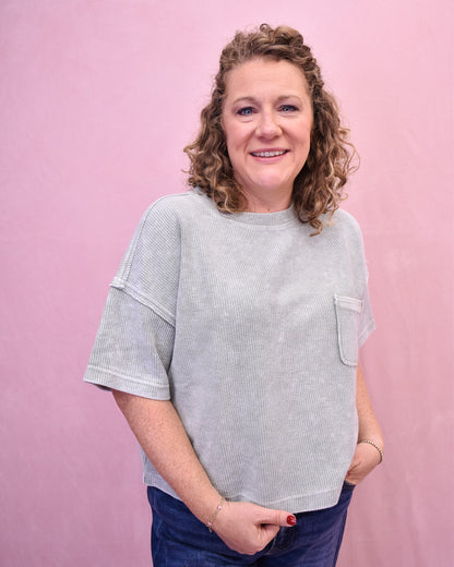 Woman wearing a light gray textured sweater against a pink background