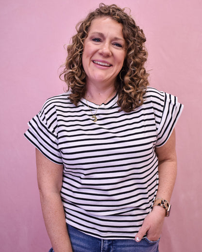 Woman wearing a black and white striped shirt against a pink background