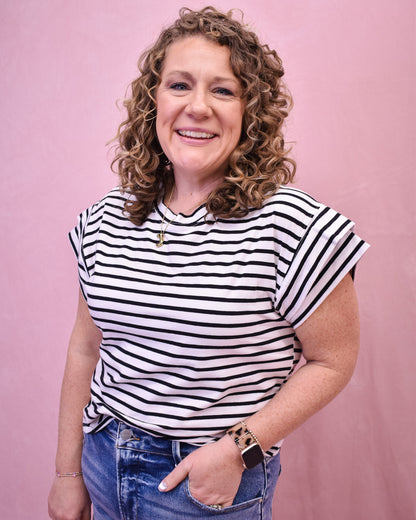 Woman wearing a black and white striped shirt against a pink background