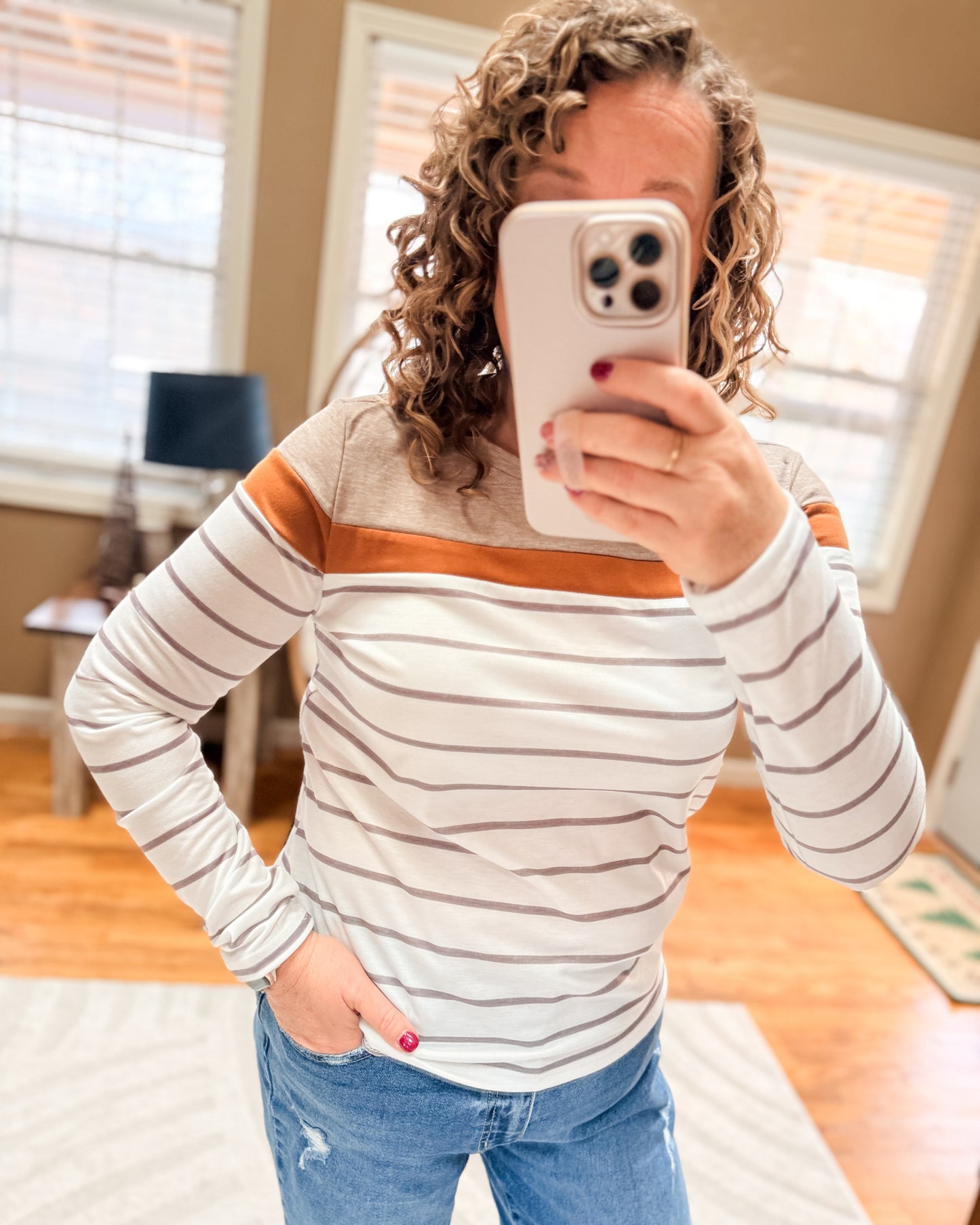 Person wearing a striped sweater and taking a mirror selfie.