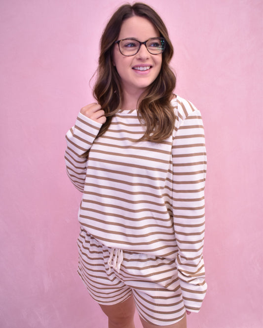 Woman wearing a striped pajama set against a pink background