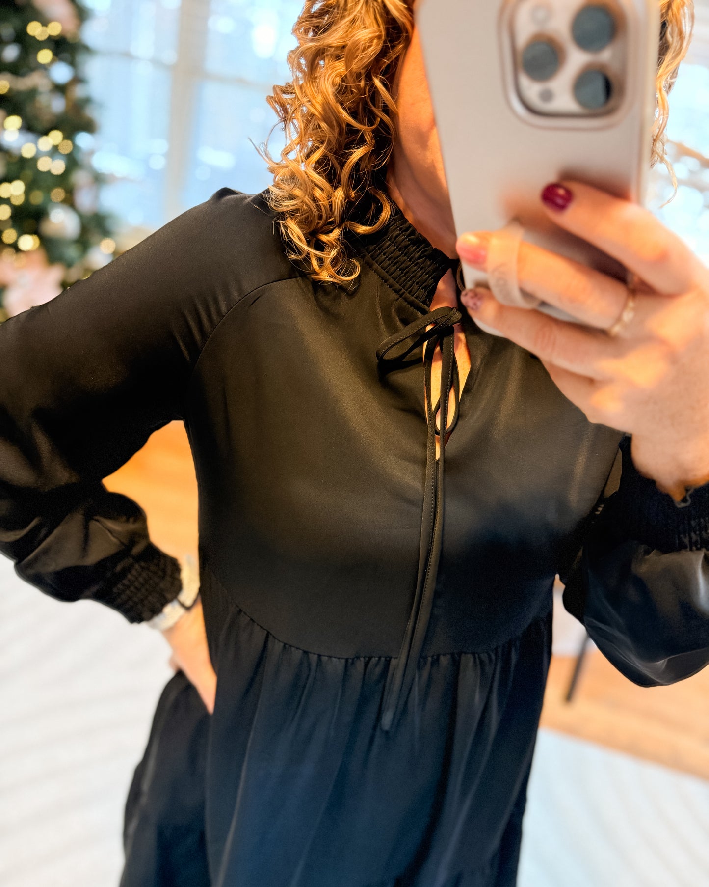 Person wearing a black top and blue skirt taking a mirror selfie.