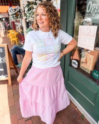 a pink and white checkered tiered midi skirt paired with a neon smiles graphic tee