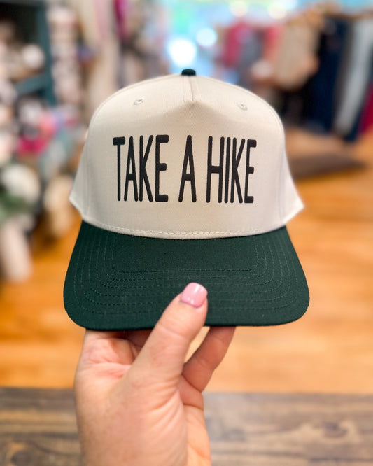 Cap with 'Take a Hike' text held by a hand in an indoor setting